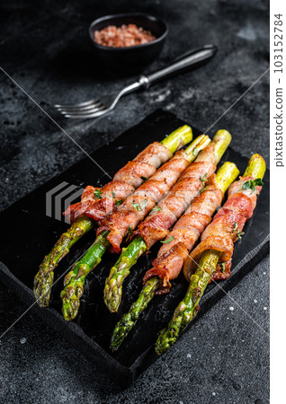 Asparagus Baked with bacon and spices. Black background. Top view 103152784