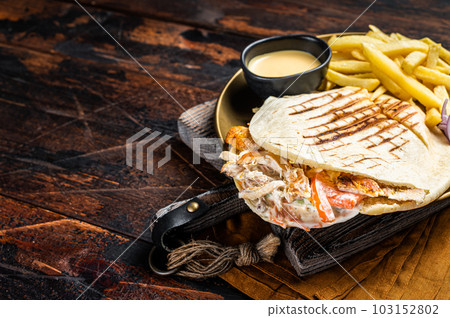 Doner kebab, Shawarma in grilled pita bread with vegetables, meat and french fry. Wooden background. Top view. Copy space Doner kebab, Shawarma in grilled pita bread with vegetables, meat and french fry. Wooden background. Top view. Copy space 103152802