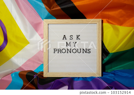 ASK MY PRONOUNS text Neo pronouns concept on Rainbow flag background gender pronouns. Non-binary people rights transgenders. Lgbtq community support assume my gender tolerance equal rights ASK MY PRONOUNS text Neo pronouns concept on Rainbow flag background gender pronouns. Non-binary people rights transgenders. Lgbtq community support assume my gender tolerance equal rights 103152914