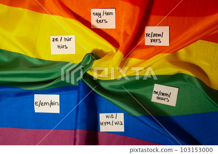 Neo pronouns concept. Rainbow flag with paper notes text gender pronouns hie, e, ne, xe, ze, tey. Non-binary people rights transgenders. Lgbtq community support assume my gender tolerance equal rights Neo pronouns concept. Rainbow flag with paper notes text gender pronouns hie, e, ne, xe, ze, tey. Non-binary people rights transgenders. Lgbtq community support assume my gender tolerance equal rights 103153000