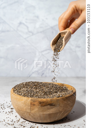 Chia seeds fall in wooden bowl. Healthy superfood rich in Omega 3 fatty acids. Dry healthy natural ingredient. Chia grains are falling Chia seeds fall in wooden bowl. Healthy superfood rich in Omega 3 fatty acids. Dry healthy natural ingredient. Chia grains are falling 103153110