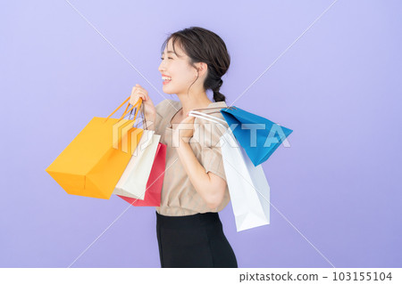 紫色背景下提著購物袋購物的年輕女子 103155104