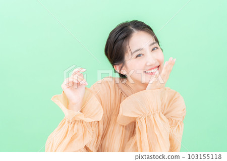 Young woman doing skin care on green background Young woman doing skin care on green background 103155118