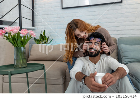 Romantic couple drinking coffeee at home relaxing in cosy living room. Romantic couple drinking coffeee at home relaxing in cosy living room. 103156414
