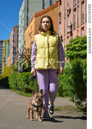 Full length townswoman walking a dog along city footpath outdoors Full length townswoman walking a dog along city footpath outdoors 103156498