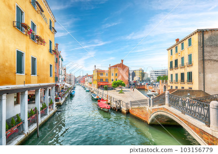 Gorgeous cityscape of Venice with narrow canals, boats and gondolas and bridges with traditional buildings 103156779