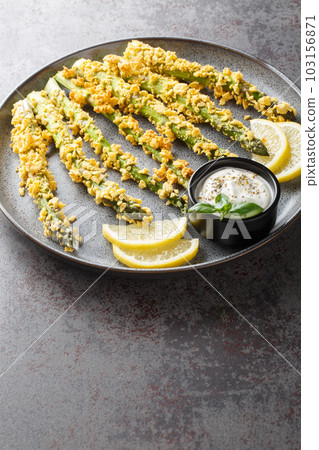 Crunchy baked asparagus fries with mayonnaise dip, healthy vegetable snack close-up on a plate. Vertical 103156871