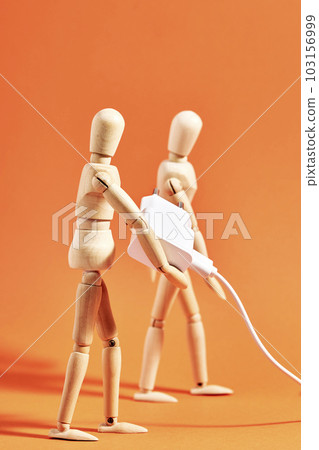 Dummy carrying a mobile phone charger on an orange background. Vertical Dummy carrying a mobile phone charger on an orange background. Vertical 103156999