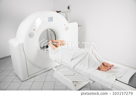Medical computed tomography or MRI scanner. Woman patient lying on couchette, waiting for doctor. Concept of medicine, healthcare and modern diagnostics. 103157279