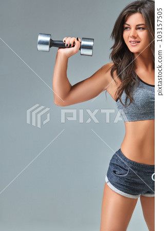 Nice sexy woman doing workout with dumbbells isolated over gray background Nice sexy woman doing workout with dumbbells isolated over gray background 103157505