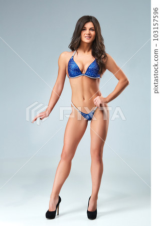 Athletic young woman posing against dark studio background Athletic young woman posing against dark studio background 103157596