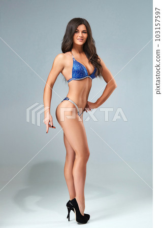 Athletic young woman posing against dark studio background Athletic young woman posing against dark studio background 103157597