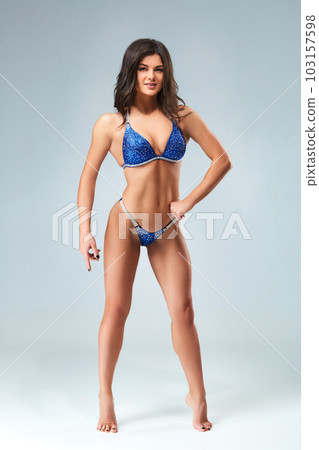 attractive girl in a blue bathing suit on grey background with perfect body. attractive girl in a blue bathing suit on grey background with perfect body. 103157598