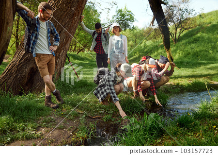 Group of young people, friends walking in forest, going hiking, resting near river on warm sunny day. Relaxation Group of young people, friends walking in forest, going hiking, resting near river on warm sunny day. Relaxation 103157723
