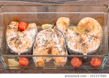 Delicious portioned steaks in a glass baking dish with lemon and tomatoes. Delicious portioned steaks in a glass baking dish with lemon and tomatoes. 103157980