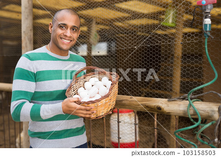 Smiling man holds a basket of chicken eggs in his hands. Smiling man holds a basket of chicken eggs in his hands. 103158503