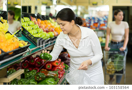 Asian woman in greengrocer s shop,picking bell pepper in small package Asian woman in greengrocer s shop,picking bell pepper in small package 103158564