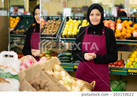 Portrait of friendly female salesperson in hijab and apron in grocery section of supermarket 103158622