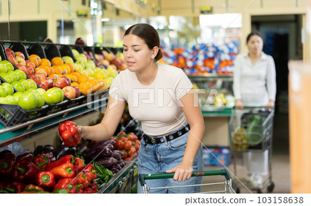 Smiling woman in greengrocer s shop,picking bell pepper in small package Smiling woman in greengrocer s shop,picking bell pepper in small package 103158638