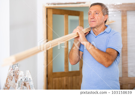 Mature man prepares place to install door in doorway Mature man prepares place to install door in doorway 103158639
