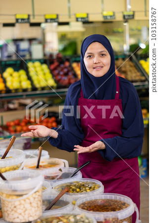 Young woman in hijab selling olives in supermarket 103158767