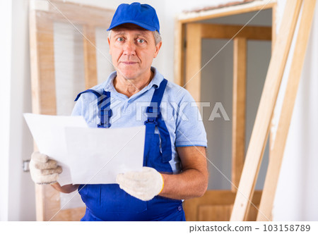 Man foreman checks the completed construction work on drawing 103158789