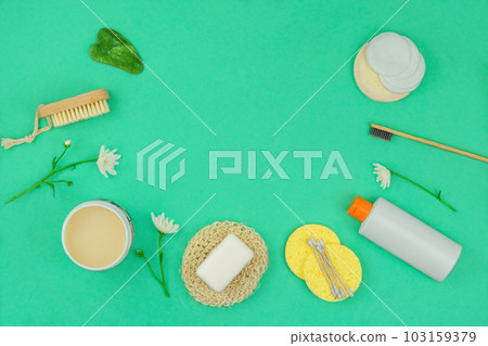Washcloths, shampoo, cream, gua sha and other accessories in green background. Top view. Copy space for text. 103159379