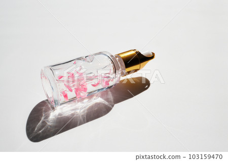 Cosmetic product bottle with rose petals and hard shadow. Skincare beauty product concept Cosmetic product bottle with rose petals and hard shadow. Skincare beauty product concept 103159470