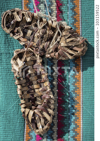 Vintage bast shoes on a green embroidered shirt. Ancient shoes. Vintage bast shoes on a green embroidered shirt. Ancient shoes. 103159522