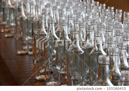 Glassworks. Glass industry. Many glass bottles on an industrial conveyor. Glassworks. Glass industry. Many glass bottles on an industrial conveyor. 103160433
