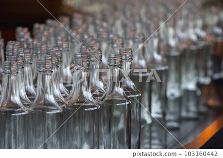 Glassworks. Glass industry. Many glass bottles on a factory conveyor. 103160442