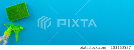 Banner. Cleaning. Flat lay green sponge and cleaning product on a blue background. Banner. Cleaning. Flat lay green sponge and cleaning product on a blue background. 103163527