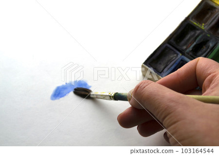 A woman paints with blue paint. A woman paints with blue paint. 103164544