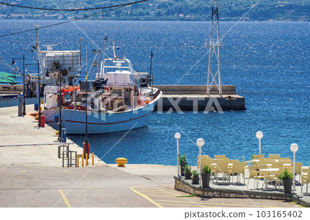 A traditional caique fishing boat with gear moored at a small port around a calm blue sea in Greece.. A traditional caique fishing boat with gear moored at a small port around a calm blue sea in Greece.. 103165402