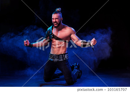 Handsome young sexy man with beautiful muscular chest in interesting costume on the scene Handsome young sexy man with beautiful muscular chest in interesting costume on the scene 103165707