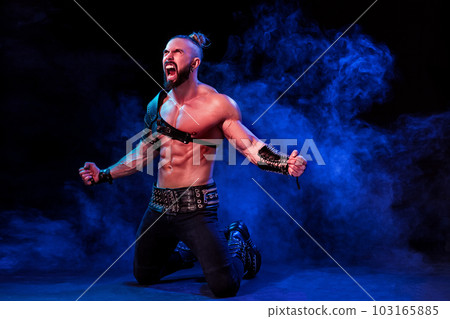 Handsome young sexy man with beautiful muscular chest in interesting costume on the scene Handsome young sexy man with beautiful muscular chest in interesting costume on the scene 103165885