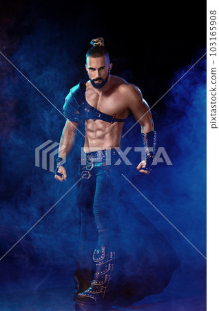 Young and muscular man performing a theatrical pose on stage. Young and muscular man performing a theatrical pose on stage. 103165908