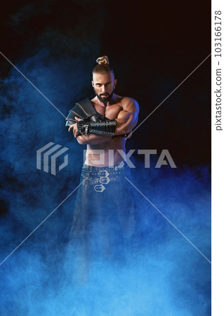 Young and muscular man performing a theatrical pose on stage. Young and muscular man performing a theatrical pose on stage. 103166178