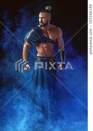 Young and muscular man performing a theatrical pose on stage. 103166189