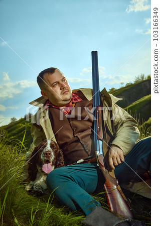 Close up portrait with handsome hunter and his dog English springer spaniel resting in forest after hunting over nature background 103166349