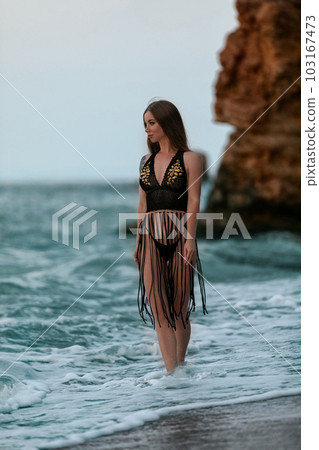Fashionable woman with slim perfect figure walking in front of blue sea. Fashionable woman with slim perfect figure walking in front of blue sea. 103167473