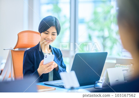 穿著西裝的中層女商人在辦公室操作智能手機 103167562