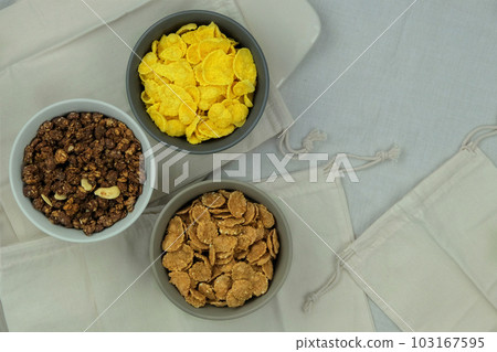 Variety of breakfast cereals and muesli in bowls on a light wooden background. Fast food. Top view. Space for text. 103167595