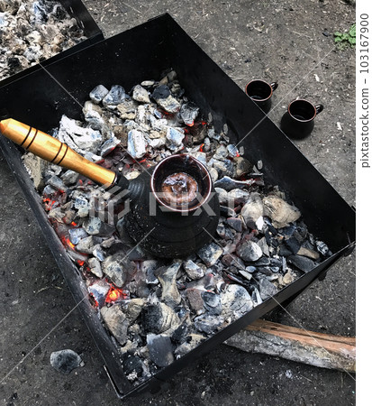 Turkish coffee on coals in the grill. Cups are on the ground. Turkish coffee on coals in the grill. Cups are on the ground. 103167900