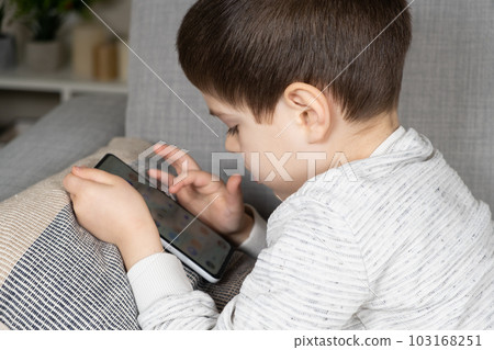 A preschool boy uses a smartphone, plays games on his phone. Screen Time, Parental Controls 103168251