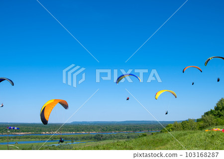 The sportsman flying on a paraglider. Paragliding Silhouette on blue sky. Paragliding take off. Travel destination. Summer and holiday concept The sportsman flying on a paraglider. Paragliding Silhouette on blue sky. Paragliding take off. Travel destination. Summer and holiday concept 103168287