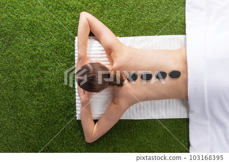 Woman lying on spa hot stone Woman lying on spa hot stone 103168395