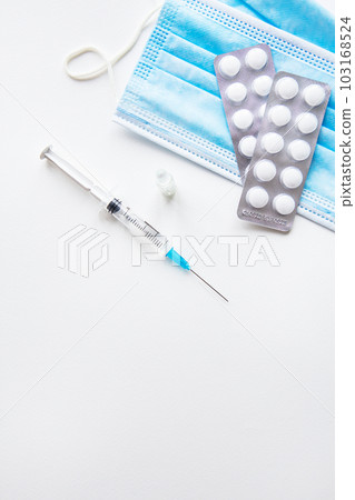 Preparation for vaccination against covid-19. Thermometer, pills, medical mask on a white table. Place for an inscription, vertical photo. 103168524