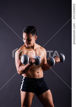 Shirtless bodybuilder showing his great body and holding dumbell. Shirtless bodybuilder showing his great body and holding dumbell. 103169002