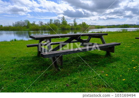 A wooden bench with a table for a picnic by the lake. Nice place to relax A wooden bench with a table for a picnic by the lake. Nice place to relax 103169494